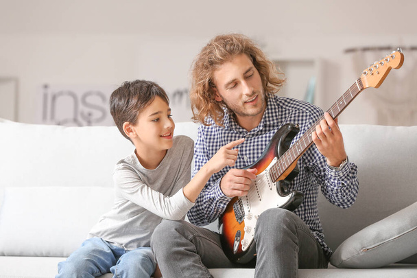 Чоловік і його син грають вдома на гітарі. - Фото, зображення