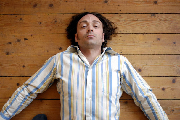 young man lying on a wooden floor - Foto, Imagen