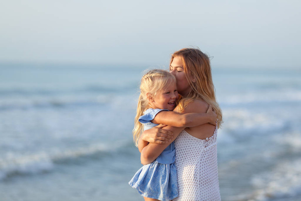 Portrait of happy sisters. They hug on the background of the sea. - Φωτογραφία, εικόνα