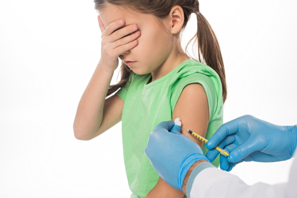 Vista laterale del pediatra che fa l'iniezione del vaccino al bambino spaventato isolato su bianco
 - Foto, immagini