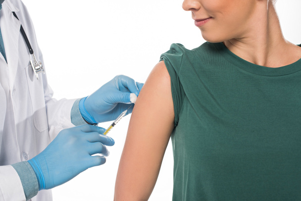 Oříznutý pohled na lékaře provádějícího očkování pacientovi izolovanému na bílém - Fotografie, Obrázek
