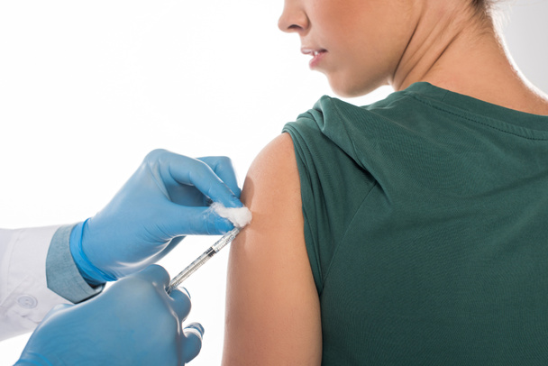 Gewassen zicht op arts met watten en injectiespuiten die vaccinatie toedienen aan patiënt geïsoleerd op wit - Foto, afbeelding