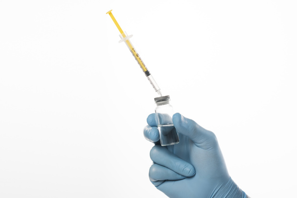 Άποψη του γιατρού στο γάντι από λατέξ που κρατά το βάζο του εμβολίου και της σύριγγας που απομονώνονται σε λευκό - Φωτογραφία, εικόνα