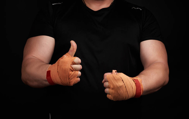 atleta muscular em uniforme preto mostra um gosto, palmas embrulhadas em
 - Foto, Imagem