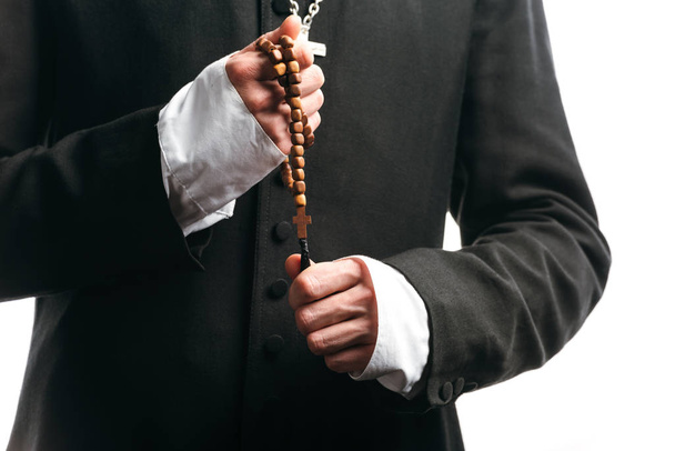 cropped view of catholic priest holding wooden rosary beads isolated on white - Foto, Bild