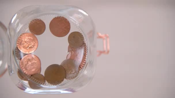 Une vue d'oeil de ver de quelqu'un laissant tomber quelques centimes dans un bocal en verre
 - Séquence, vidéo
