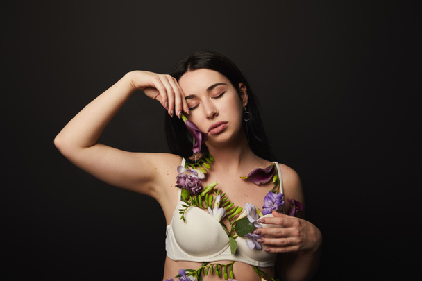 tender beautiful girl in bra with violet and purple flowers on body isolated on black - Foto, immagini