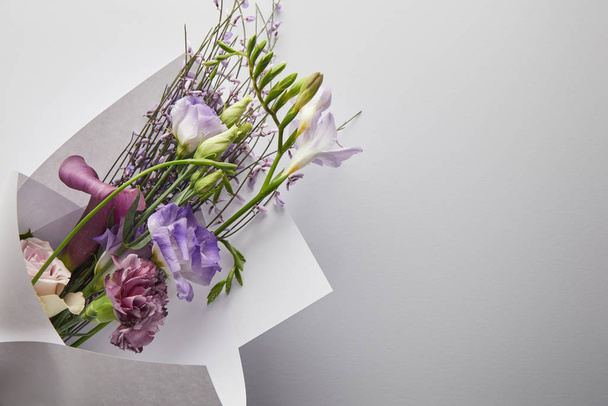 top view of violet bouquet wrapped in paper on white background - Fotoğraf, Görsel