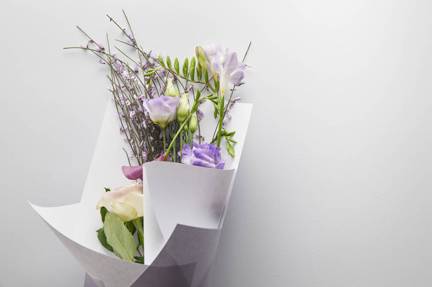 top view of violet bouquet wrapped in paper on white background - 写真・画像