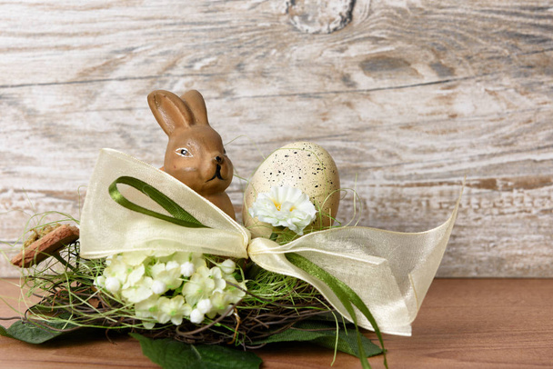 easter bunny with easter egg in nest in front of wood background as an easter greeting with free text space - Φωτογραφία, εικόνα