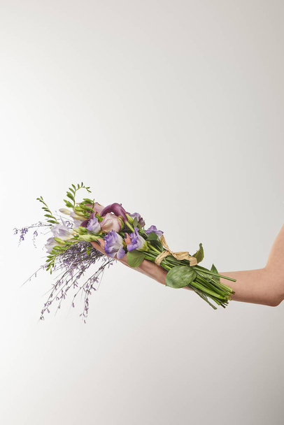 cropped view of woman holding bouquet of violet and purple flowers on white - Foto, Imagen