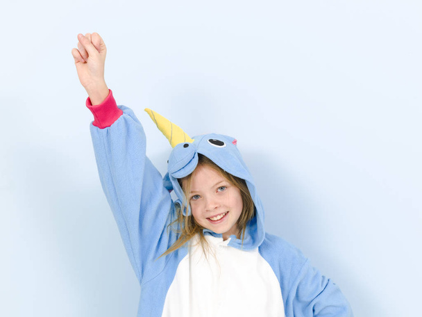 happy pretty blonde girl in cozy unicorn costume in studio on blue background  - Фото, зображення