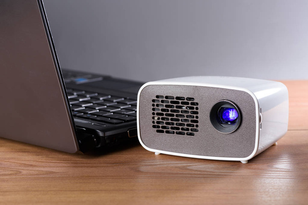 battery operated mini projector with a notebook on a desk. the transfer of the image is done wirelessly. - Φωτογραφία, εικόνα