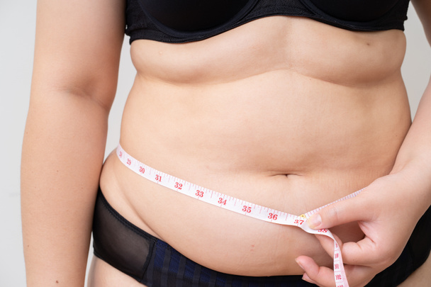 Надмірна вага жінки зі стрічкою, що вимірює її живіт
 - Фото, зображення