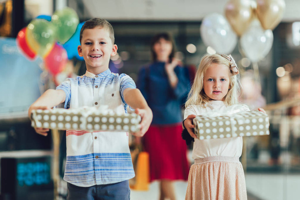 Petite fille et garçon tenant des cadeaux dans le centre commercial, s'amuser w
 - Photo, image