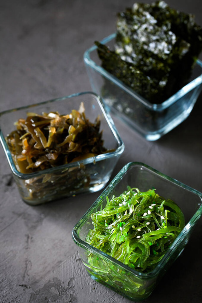 Traditional Japanese Chuka Wakame seaweed salad and crispy roasted nori sheets in glass bowl on dark background - Foto, immagini