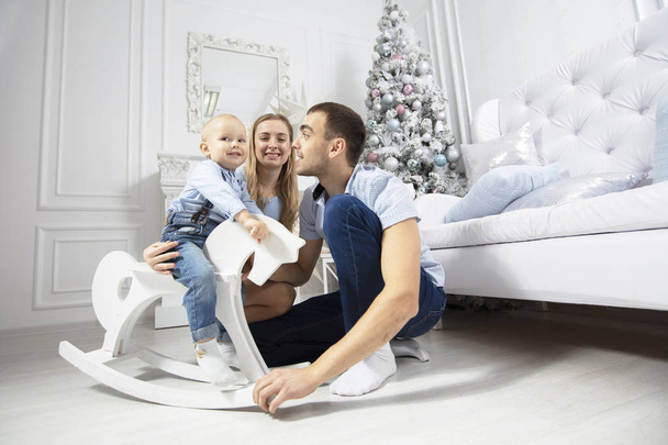 Семья на Рождество. Мать отец и ребенок играют на фоне рождественской елки. Родители и сын в новом году
. - Фото, изображение