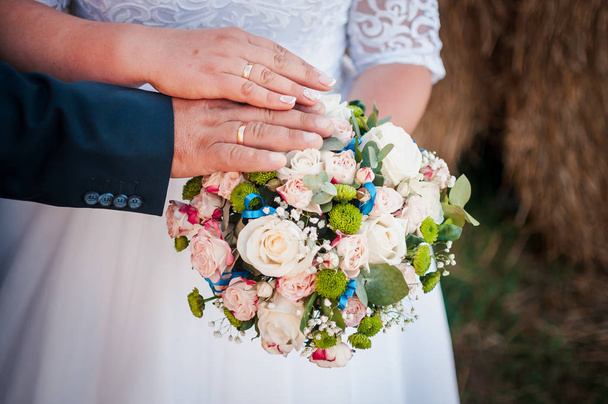 A vőlegény és a menyasszony keze a virágcsokron nyugszik. - Fotó, kép