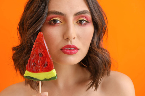 Beautiful young woman with lollipop on color background - Photo, Image