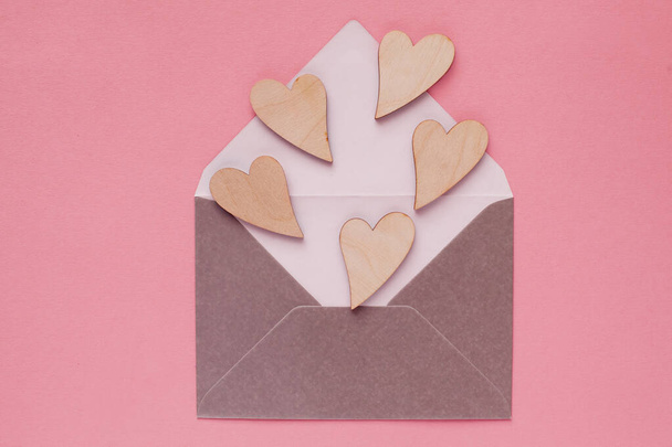 Drewniane, piękne serca w papierowej kopercie, przesłanie miłosne na Walentynki i kobiece dni. Pocztówka, powitanie, widok z góry - Zdjęcie, obraz
