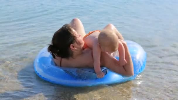 Mãe com seu bebê nadando no mar com anel inflado
 - Filmagem, Vídeo