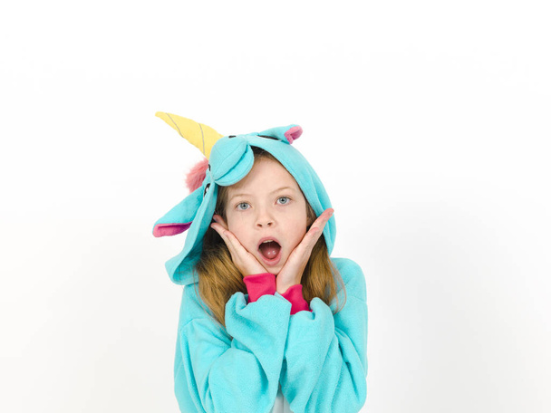 happy pretty blonde girl in cozy unicorn costume in studio on blue background  - Foto, Imagem