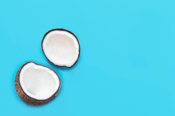 Two halves of coconut, open coconut cut in half isolated on blue background. Coconut pulp is very healthy wholesome food. Top view, copy space, place for text. - Valokuva, kuva