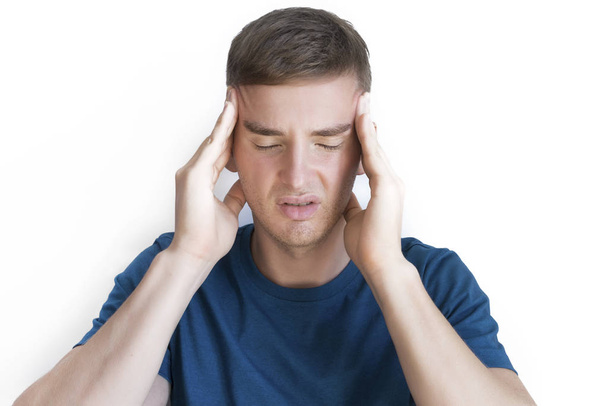 Person suffering from feeling sick, ill, pain because severe headache, migraine. Handsome guy, young sad upset man holding his head with hand, looking at camera. Bad sad negative mood, face expression - Фото, изображение