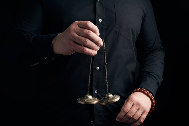 homem adulto em roupas pretas segura em suas mãos um par de bronze K
 - Foto, Imagem