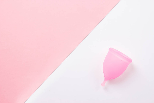 Copa menstrual rosa sobre fondo rosa y blanco. Asiento plano, vista superior. espacio de copia
. - Foto, imagen