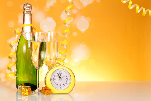 Esperando las vacaciones, la botella de champán y el reloj en el fondo de la mesa
 - Foto, Imagen