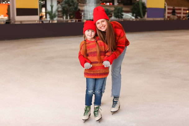 Jonge moeder met dochtertje op schaatsbaan - Foto, afbeelding