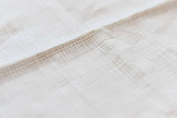Puha világos szürke természetes vászon textúra összpontosítva a fold. Gyűrött szövet háttér. Szelektív fókusz. Közelkép - Fotó, kép