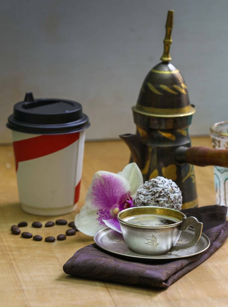 Çay tabağı espresso, orkide çiçeği, yemek odası peçetesinde servis edilen kahve ve kağıt bardakta duran fasulye kalbi. - Fotoğraf, Görsel