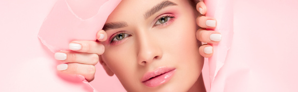 tiro panorâmico de bela jovem com maquiagem rosa em papel rasgado, isolado em rosa
 - Foto, Imagem
