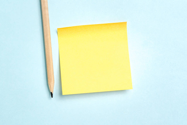 Žlutá prázdná papírová zpráva s tužkou na modrém pozadí - Fotografie, Obrázek