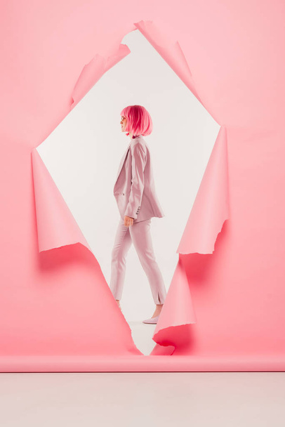 stylish woman in suit and pink wig posing in torn paper, on white - Foto, Imagem