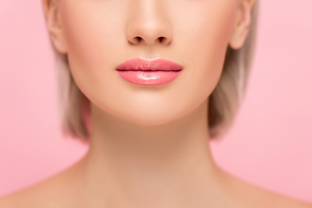 καλλιεργημένη άποψη της νεαρής γυναίκας με τέλειο δέρμα και ροζ χείλη, απομονωμένη σε ροζ - Φωτογραφία, εικόνα