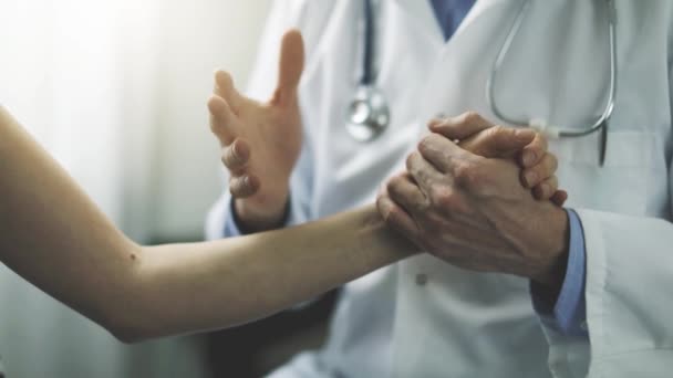 médico hablando sobre el diagnóstico mientras sostiene la mano del paciente en el consultorio clínico
 - Metraje, vídeo
