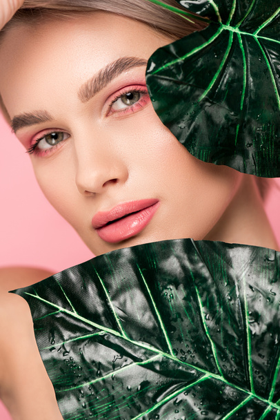 tender girl with pink makeup isolated on pink with green leaves  - Fotoğraf, Görsel