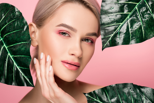 atractiva chica tierna con maquillaje rosa aislado en rosa con hojas verdes
  - Foto, imagen