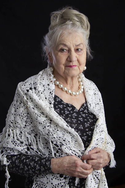 Portrait of a ninety year old woman. Beautiful old lady. Luxurious grandmother on a black background. Elderly beauty. The gray-haired well-groomed pensioner. - Photo, Image