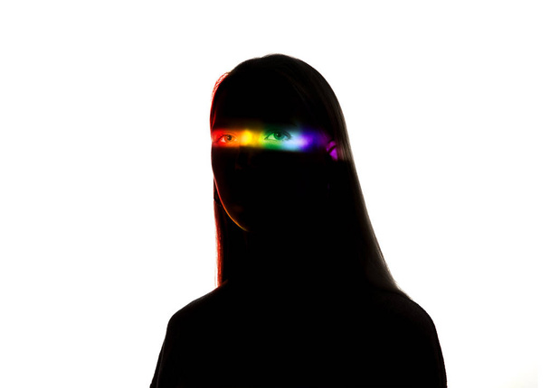 Dramatic portrait of a girl in the dark on white studio background with rainbow colored line - Photo, image