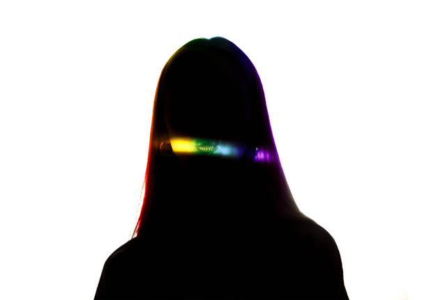 Dramatic portrait of a girl in the dark on white studio background with rainbow colored line - Foto, Imagem