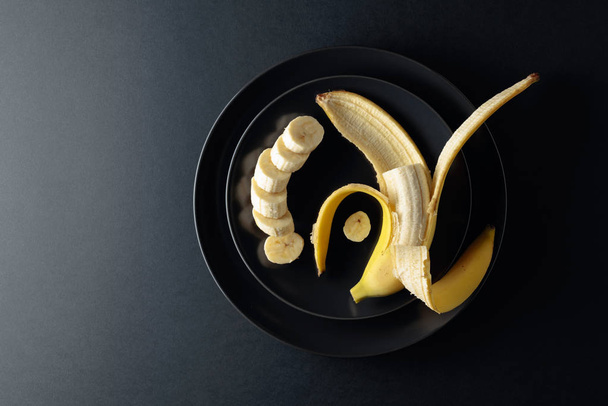 Ripe juicy banana on a black plate.  - Foto, Imagem