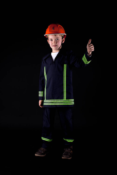 portrait of a young engineer in a suit with a helmet on a black background - Foto, Imagem