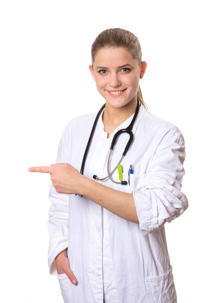 female doctor in a white coat smiling at camera and pointing to the left with her index finger - Foto, Imagem
