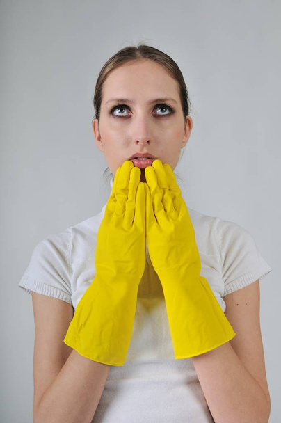 Young woman wearing yellow work gloves with thoughtful expression - Foto, Imagem