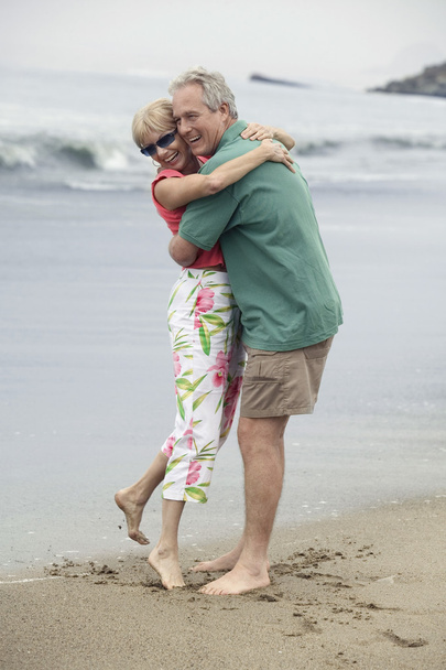 Paar mittleren Alters umarmt sich am Strand - Foto, Bild