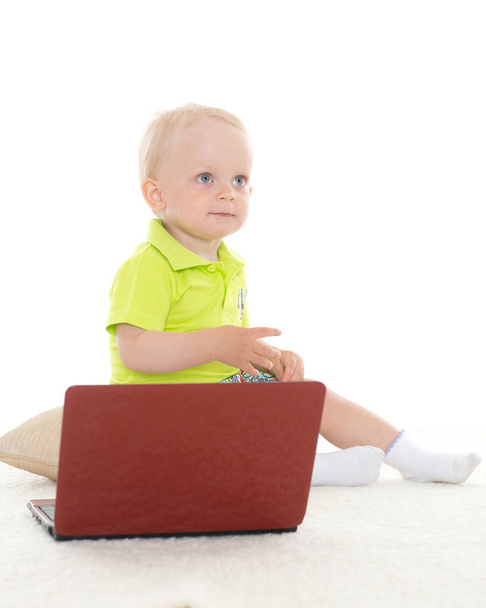 Sweet yearling baby boy  with laptop sits on the floor on a white background. - Fotografie, Obrázek